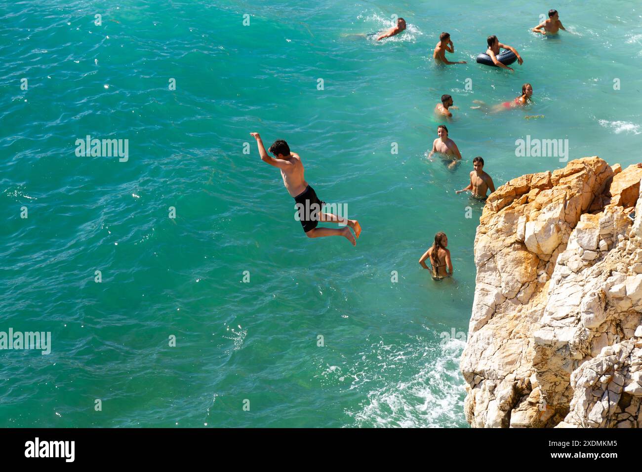 Bambini che saltano da una scogliera nel Mar Mediterraneo Foto Stock