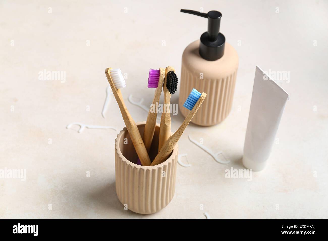 Tazza con spazzolini da denti, tubetto di dentifricio e dispenser per sapone su fondo grunge beige Foto Stock