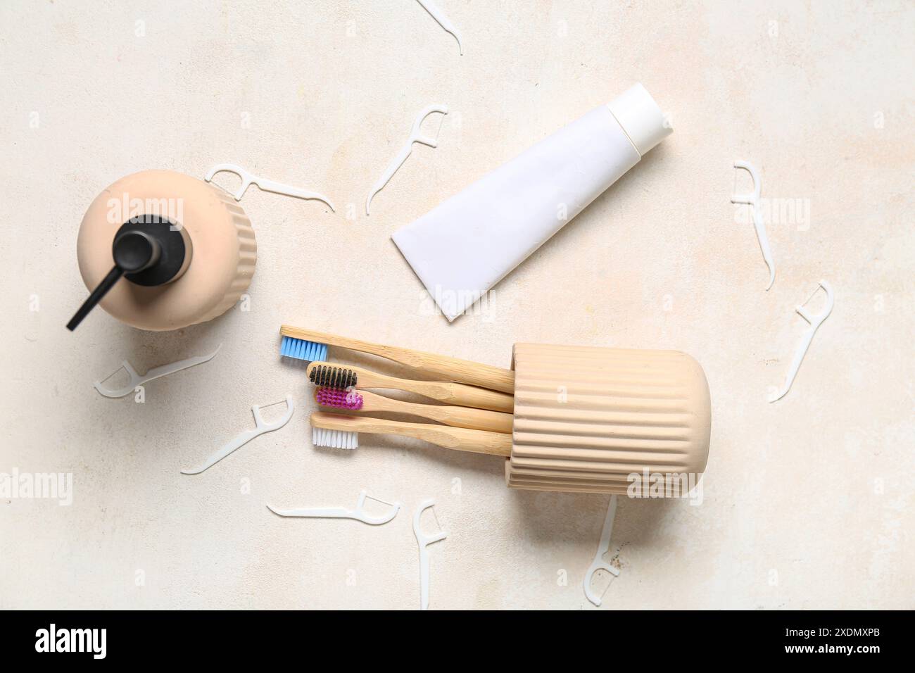 Tazza con spazzolini da denti, tubetto di dentifricio e dispenser per sapone su fondo grunge beige Foto Stock