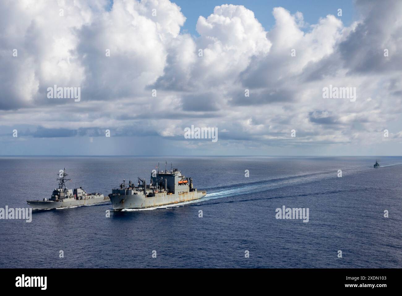 240618-N-NF288-097 SOUTH CHINA SEA (18 giugno 2024) il cacciatorpediniere missilistico guidato classe Arleigh Burke USS Ralph Johnson (DDG 114), a sinistra, conduce un rifornimento in mare con USNS Wally Schirra (T-AKE-8), centro, durante operazioni bilaterali con la fregata classe Halifax della Royal Canadian Navy HMCS Montreal (FFH 336) nel Mar Cinese meridionale, 18 giugno 2024. Operazioni combinate come questa hanno lo scopo di migliorare l'interoperabilità tra le marine alleate e supportare un Indo-Pacifico libero e aperto. Ralph Johnson è schierato in avanti e assegnato al Destroyer Squadron (DESRON) 15, il più grande DESRON della Marina e TH Foto Stock