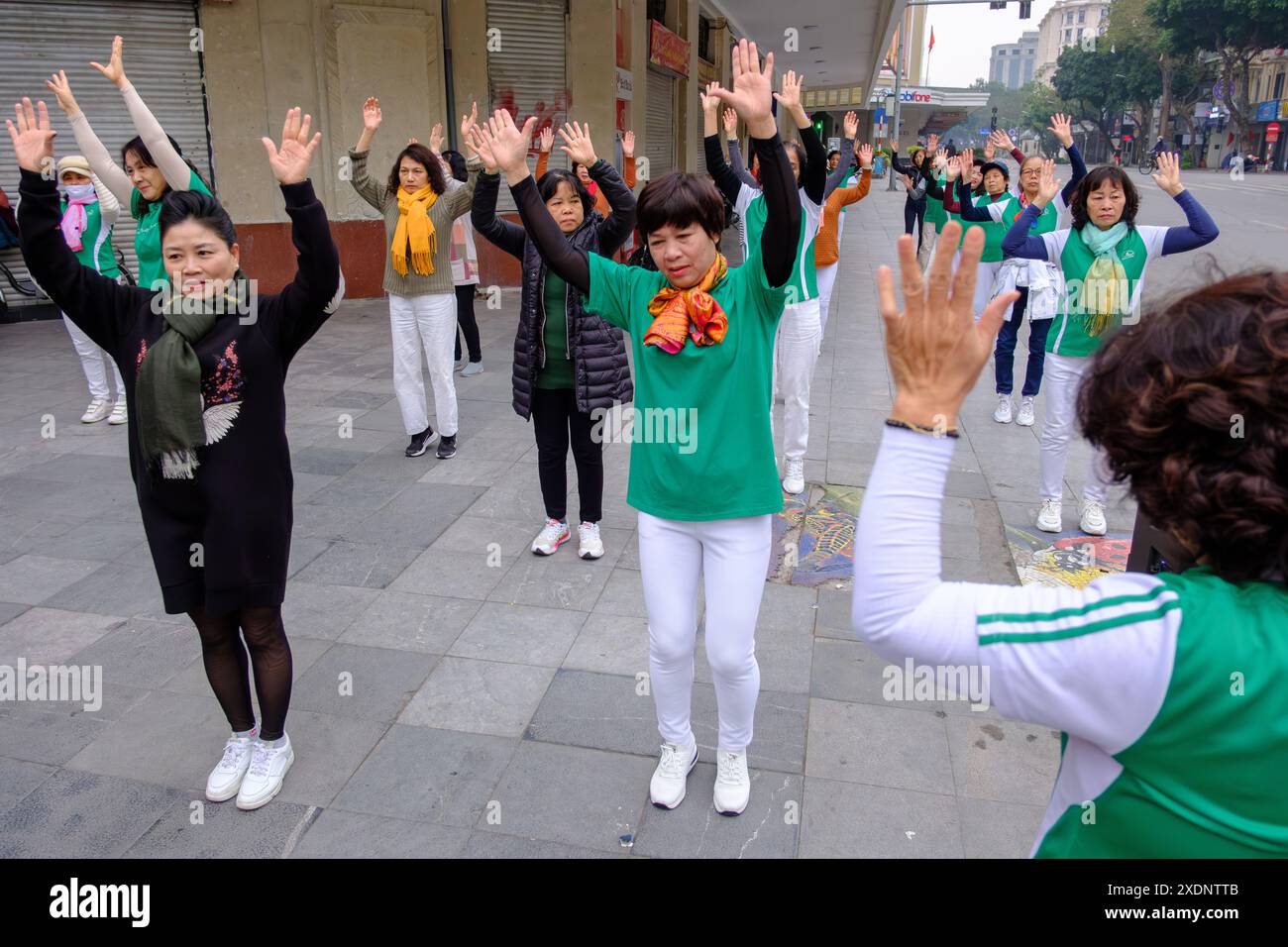 Un gruppo di donne danzano la mattina presto vicino al lago Hoan Kiem ad Hanoi Foto Stock