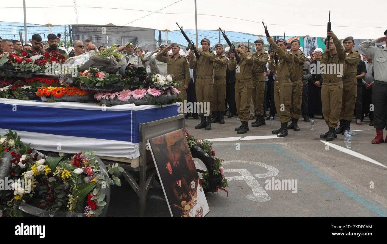 BEIT JAAN, ISRAELE - 16 GIUGNO: i soldati israeliani sparano un saluto mentre si trovano accanto al cofanetto drappeggiato di bandiera di un soldato IDF caduto e un membro della comunità drusa israeliana, il capitano Wassem Mahmoud, ucciso vicino alla città meridionale di Gaza, Rafah, durante il suo funerale il 16 giugno 2024 a Beit Jann, Israele. Il capitano Wassem Mahmoud, 23 anni, di Beit Jaan, è stato uno degli otto soldati israeliani uccisi ieri, quando una portaerei blindata è esplosa a Rafah, nella Striscia di Gaza meridionale. Foto Stock