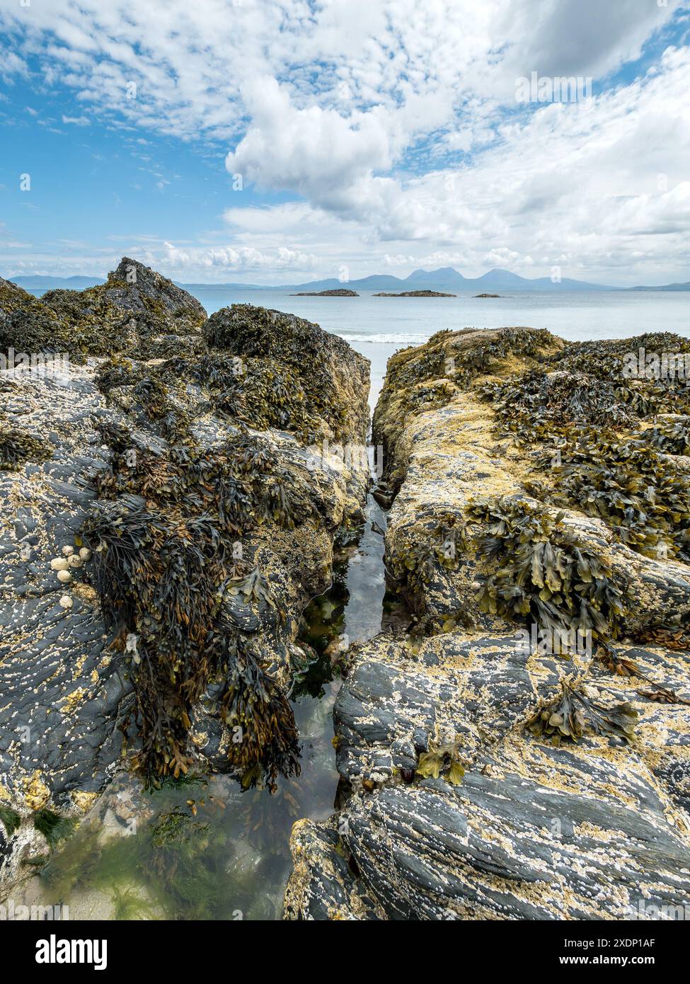 Le montagne Paps of Jura sono visibili all'orizzonte dalla spiaggia di Port a Chapuill sulla vicina isola di Colonsay nelle Ebridi interne, Scozia, Regno Unito Foto Stock