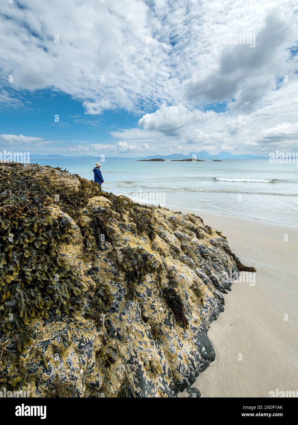 Le montagne Paps of Jura sono visibili all'orizzonte dalla spiaggia di Port a Chapuill sulla vicina isola di Colonsay nelle Ebridi interne, Scozia, Regno Unito Foto Stock