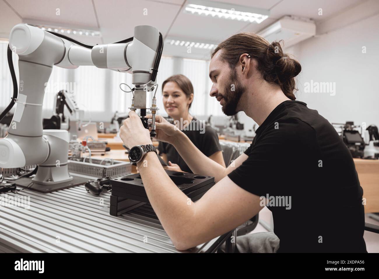 Programma di robotica industriale studenti universitari che imparano l'assemblaggio meccanico con robot Universal Training Platform mod di simulazione braccio robotico Foto Stock