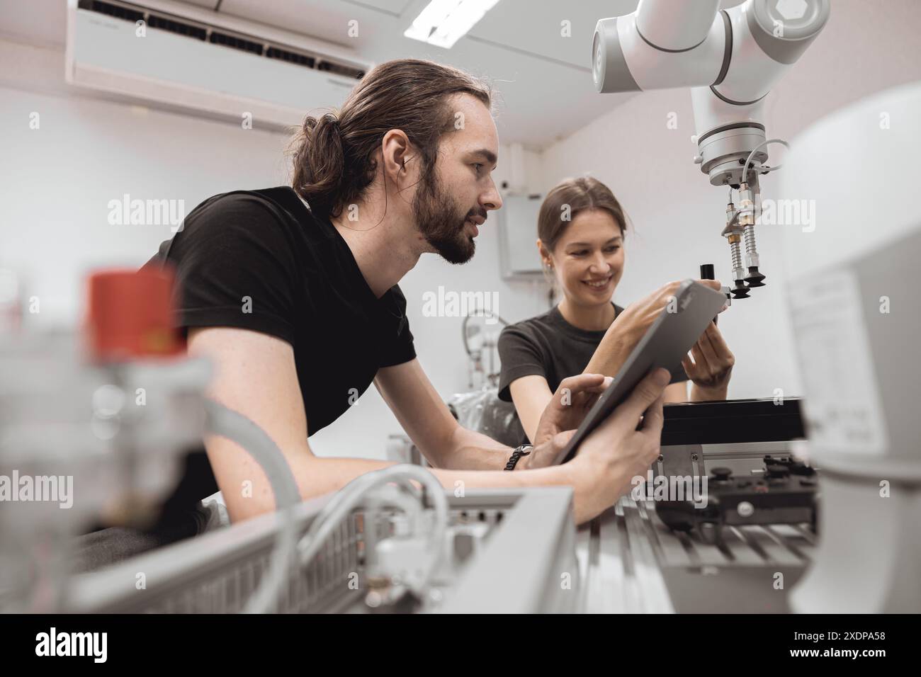 Programma di robotica industriale studenti universitari che imparano l'assemblaggio meccanico con robot Universal Training Platform mod di simulazione braccio robotico Foto Stock