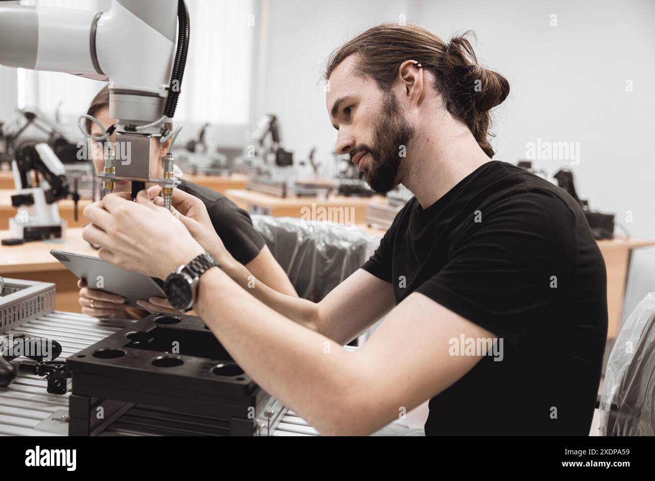 Programma di robotica industriale studenti universitari che imparano l'assemblaggio meccanico con robot Universal Training Platform mod di simulazione braccio robotico Foto Stock