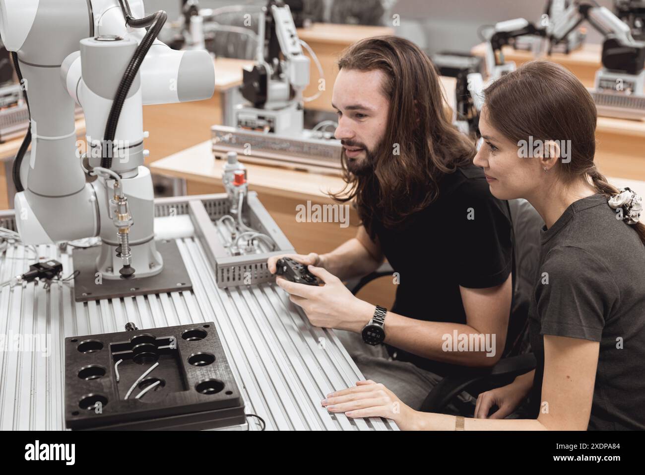 Programma di robotica industriale studenti universitari che imparano l'assemblaggio meccanico con robot Universal Training Platform mod di simulazione braccio robotico Foto Stock