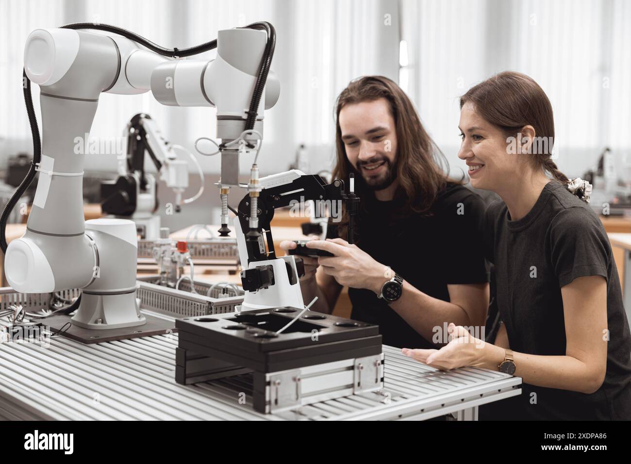 Programma di robotica industriale studenti universitari che imparano l'assemblaggio meccanico con robot Universal Training Platform mod di simulazione braccio robotico Foto Stock