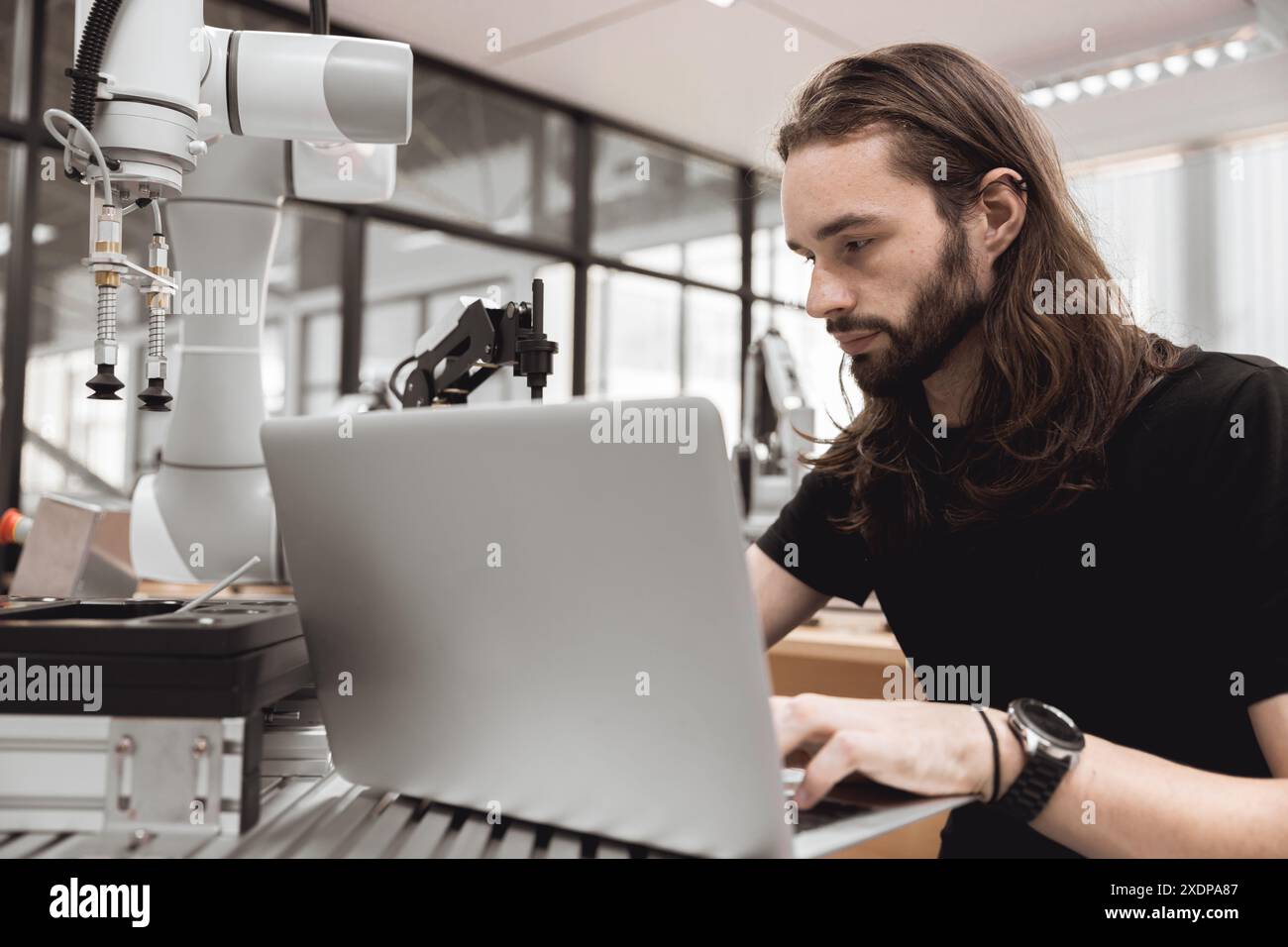 Ingegnere uomo studente universitario imparare controllo operare e programmare il braccio robotico industriale con computer portatile in robotica ingegneri laboratorio in aula in polit Foto Stock