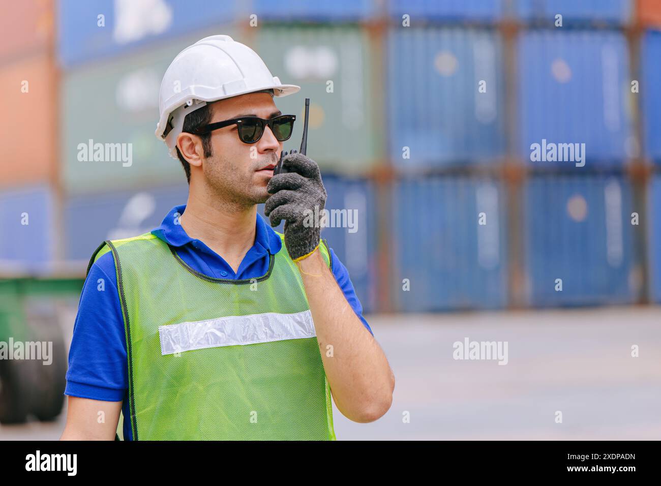 Gli ispanici lavoratori portuali che lavorano radiocontrollori operano nel deposito doganale di container per il trasporto merci portuale. Foto Stock