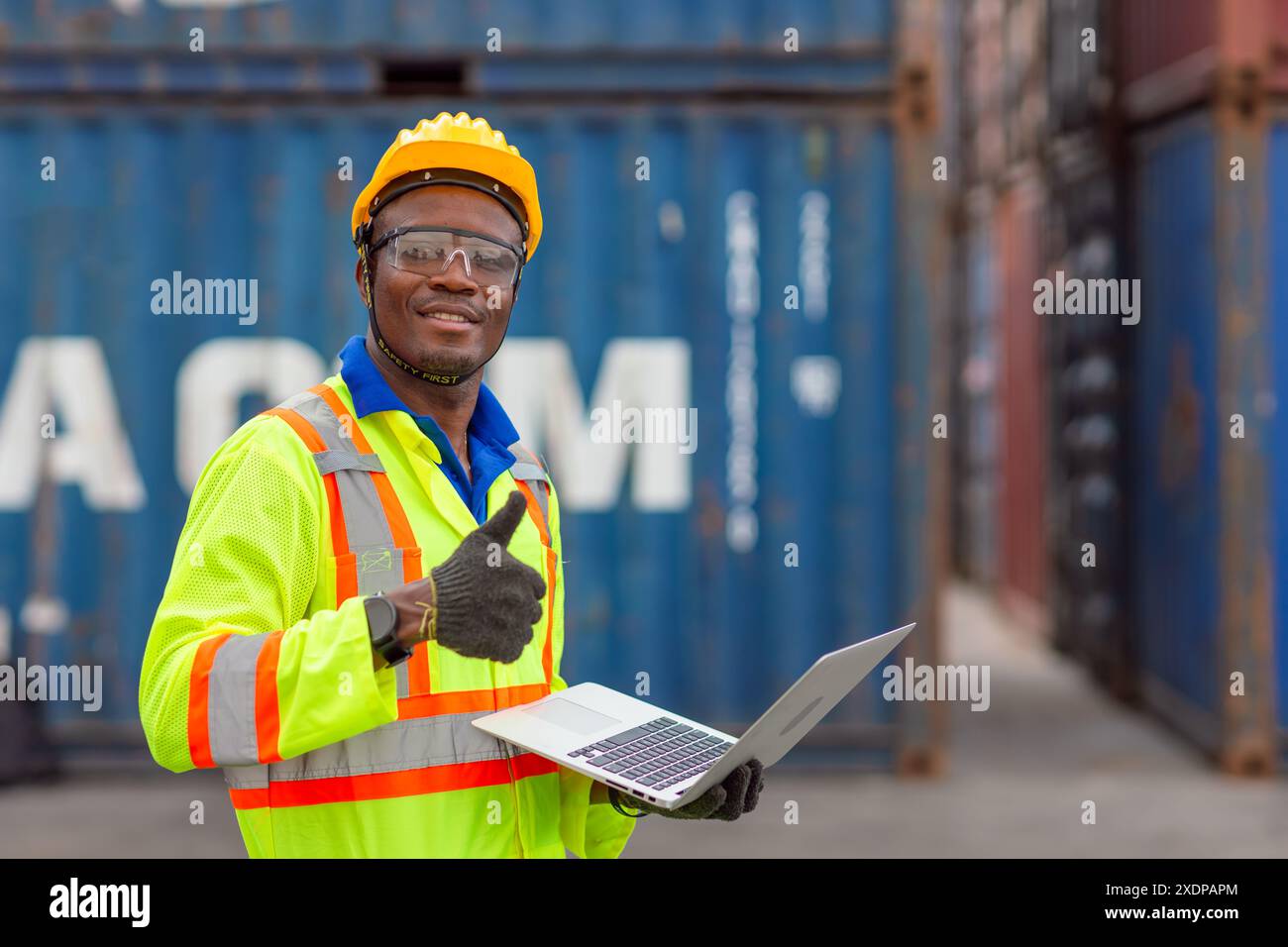 Ritratti Happy African Black Worker nel settore delle spedizioni in porto di carico con giubbotto di sicurezza Hard Hat. Caposquadra o supervisore nel terminal di imbarco delle navi container. Foto Stock