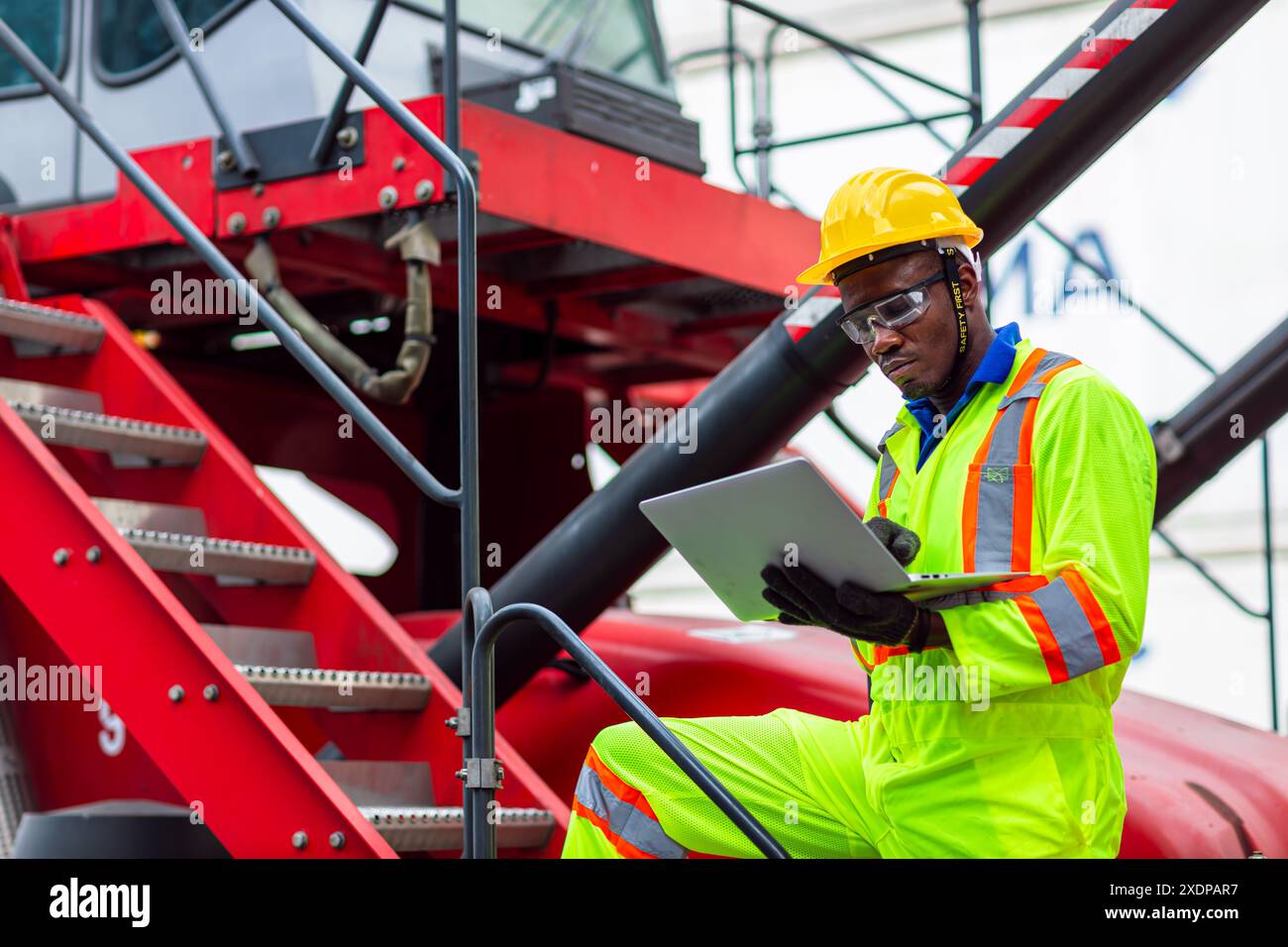 Lavoratore nero africano nel porto di carico Shipping Industrial in Yellow Hard Hat Safety Vest on Duty. Caposquadra o supervisore nel terminal di imbarco delle navi container. Foto Stock