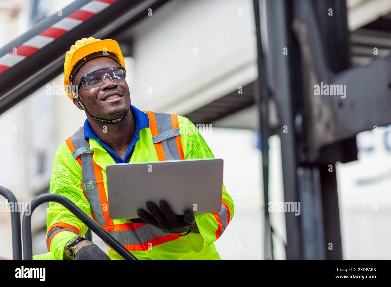 Ritratti Happy African Black Worker nel settore delle spedizioni in porto di carico con giubbotto di sicurezza Hard Hat. Caposquadra o supervisore nel terminal di imbarco delle navi container. Foto Stock