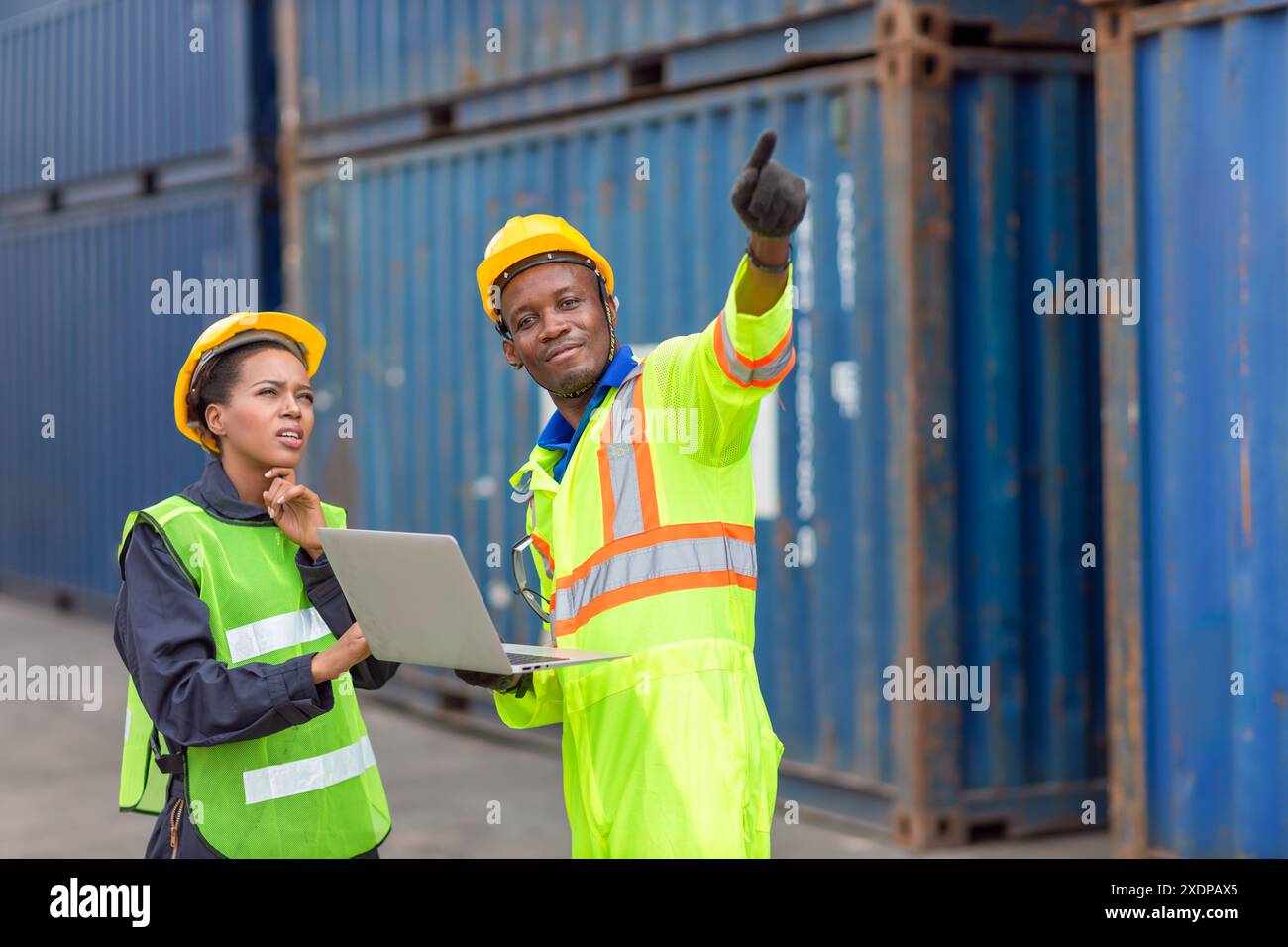 African Black Worker Teamwork in Cargo Port Shipping Industrial in Yellow Hard Hat Safety Vest On Duty. Caposquadra o supervisore nel cantiere di spedizione container T. Foto Stock