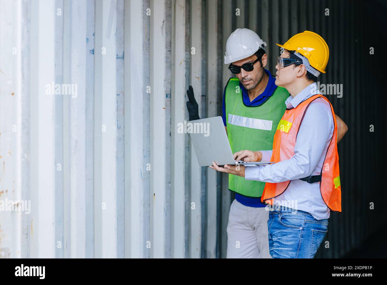 Il team di ingegneri dell'autorità portuale controlla le condizioni dell'armadietto del contenitore di carico per la sicurezza in conformità alla regola e agli standard intermodali. Foto Stock