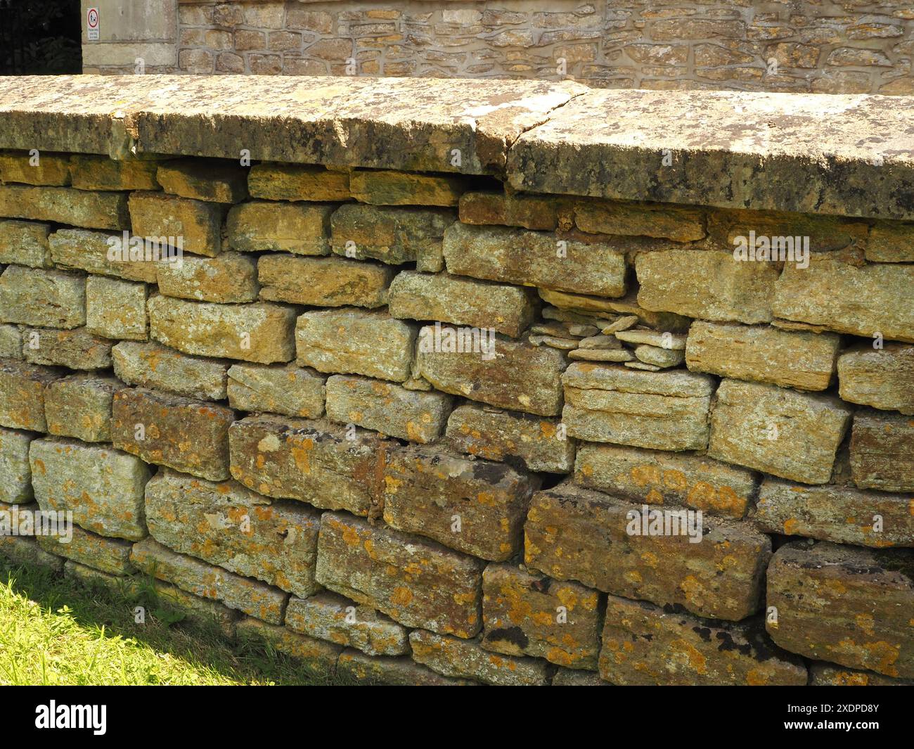 Primo piano di un muro di pietra secca con crescite di licheni, cimitero di St Michael, Melksham, Wiltshire. Muratura tradizionale. pareti in pietra a secco. Cotswold Stone. Foto Stock