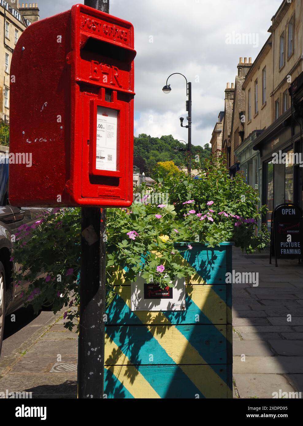 Ufficio postale rosso scatola postale reale posta montata su lampione, con piantagione di fiori di strada sotto, in Walcot Street, Bath, Somerset. Foto Stock