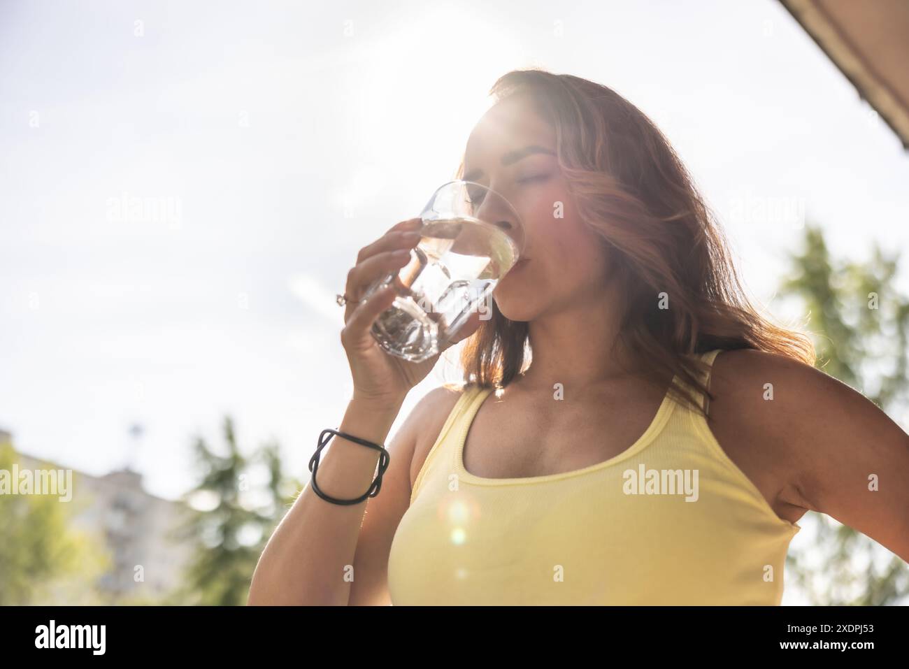 La donna disidratata beve acqua pulita da un bicchiere per riempire i fluidi durante le calde giornate estive. Foto Stock