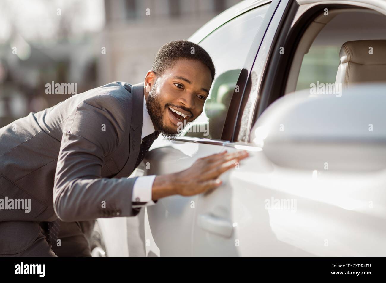 Uomo eccitato che si infila sulla sua nuova auto il giorno della domenica Foto Stock