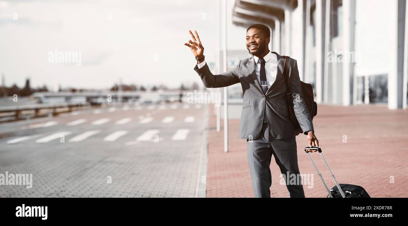 Prendi il taxi. Un uomo d'affari afro che chiama un taxi all'aeroporto Foto Stock