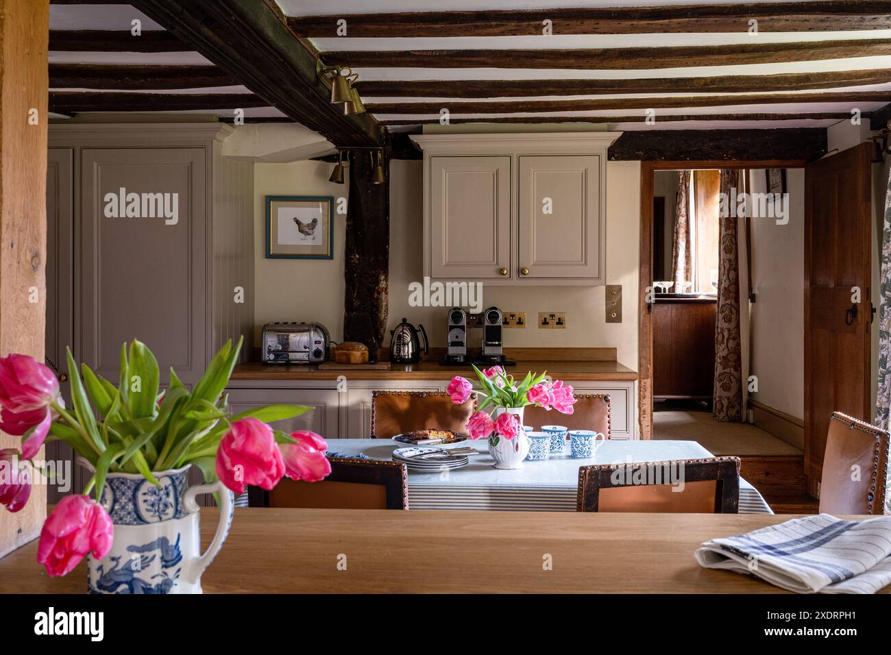 Tulipani rosa nella cucina a travi della fattoria Tudor del XVI secolo, Hertfordshire, Inghilterra, Regno Unito. Foto Stock