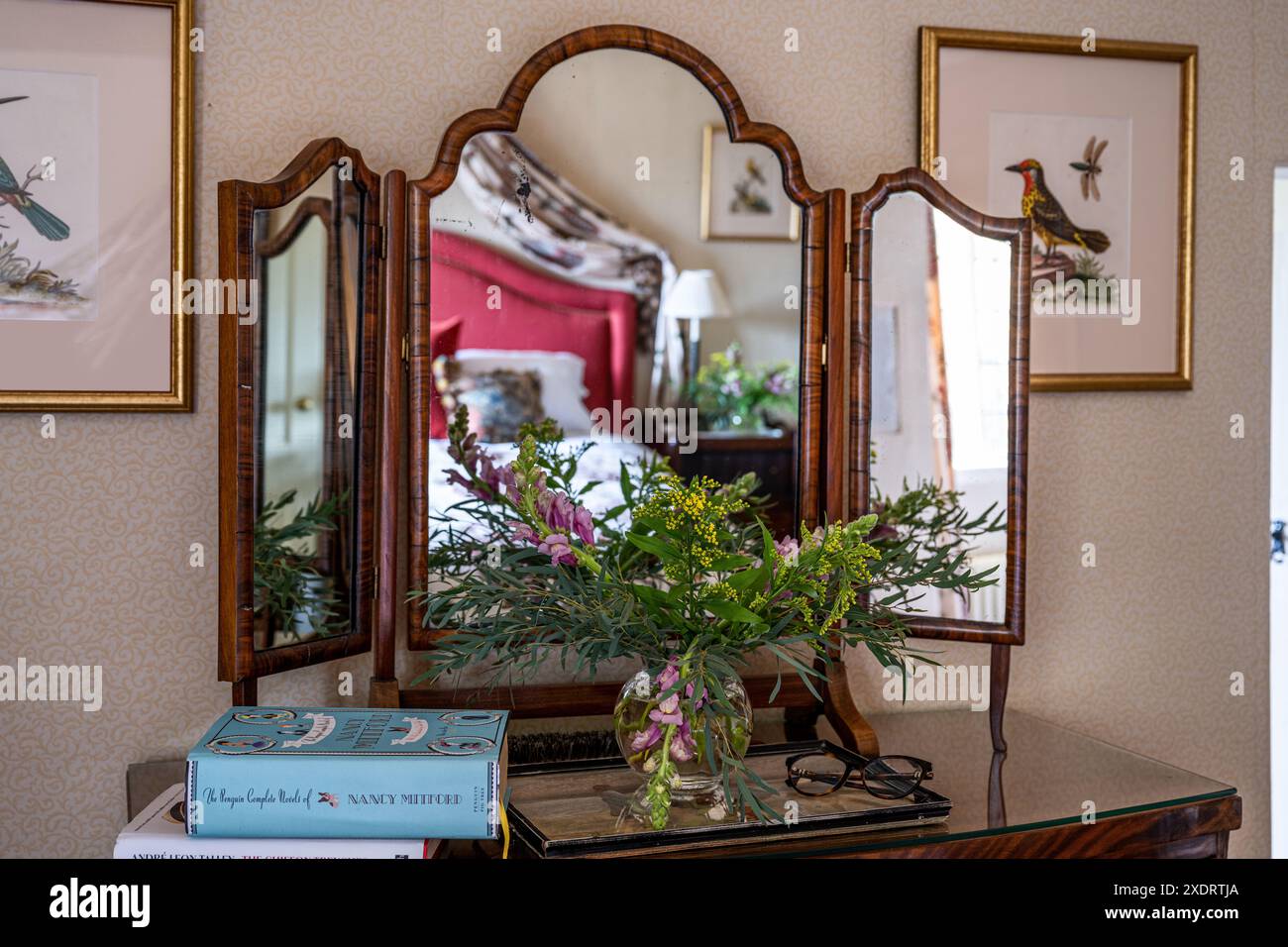 Fiori recisi e libri con specchio vintage nella fattoria Tudor del XVI secolo, Hertfordshire, Inghilterra, Regno Unito. Foto Stock