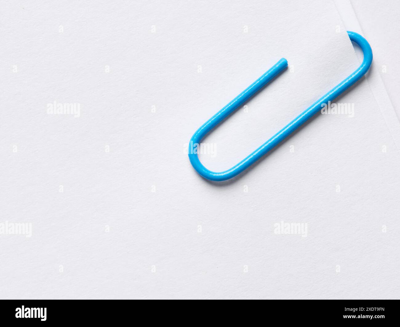 Graffetta blu attaccata alla pila di carta bianca bianca bianca. Vista a layout piatto e ravvicinato con spazio di copia. Foto Stock
