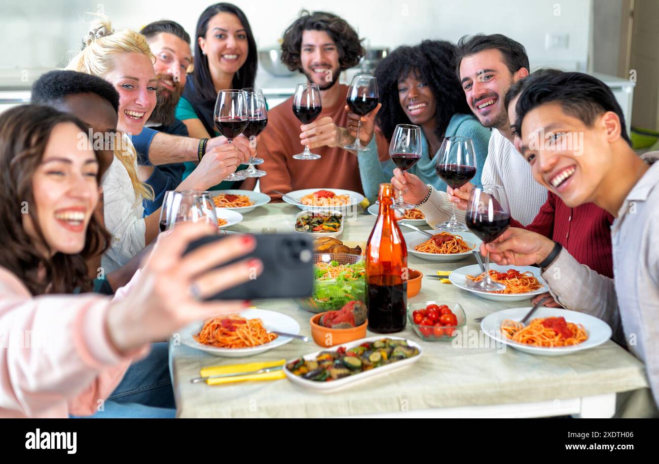 gruppo di giovani amici che festeggiano a casa mangiando e bevendo alcolici mentre fanno un selfie Foto Stock