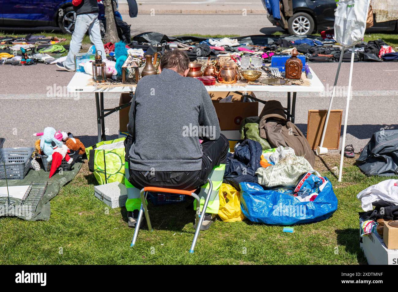 Uomo che vende beni usati al mercato delle pulci pop-up all'aperto di Dallapé Park nel quartiere Vallila di Helsinki, Finlandia Foto Stock