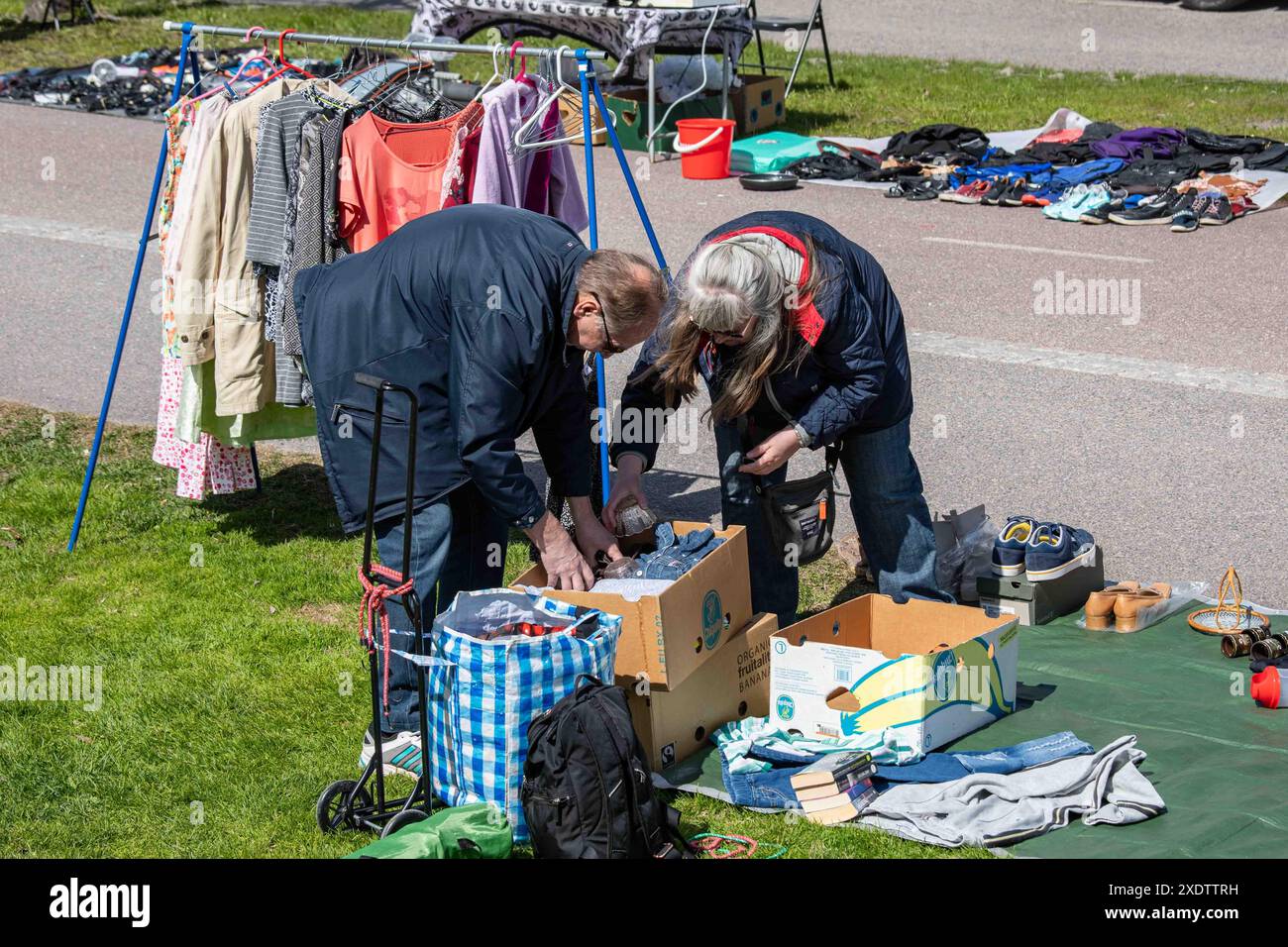 Venditori che confezionano merci usate al mercato delle pulci pop-up all'aperto del parco Dallapé nel quartiere Vallila di Helsinki, Finlandia Foto Stock