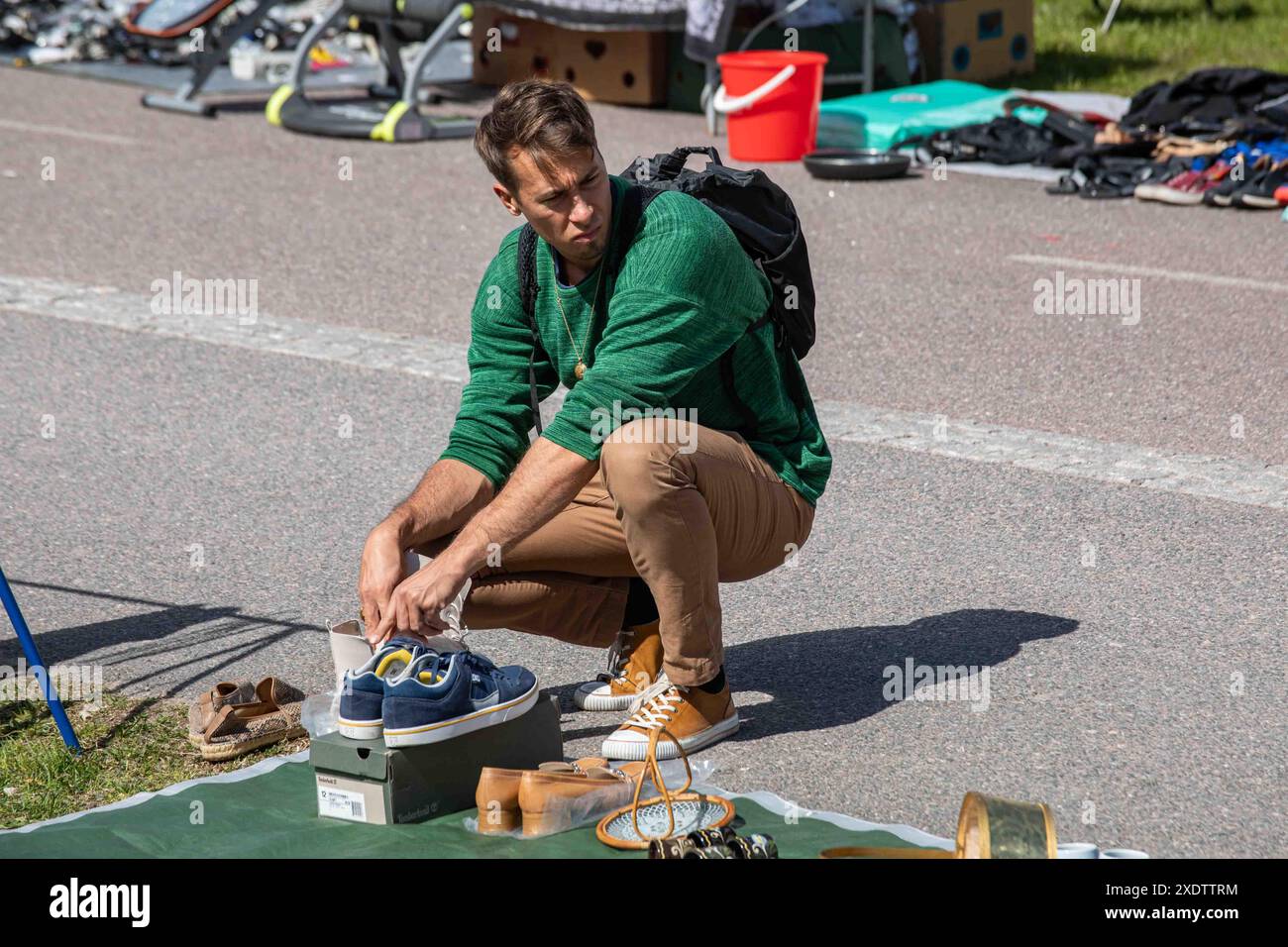 Uomo che naviga e valuta beni usati al mercato delle pulci pop-up all'aperto del Dallapé Park nel quartiere Vallila di Helsinki, Finlandia Foto Stock