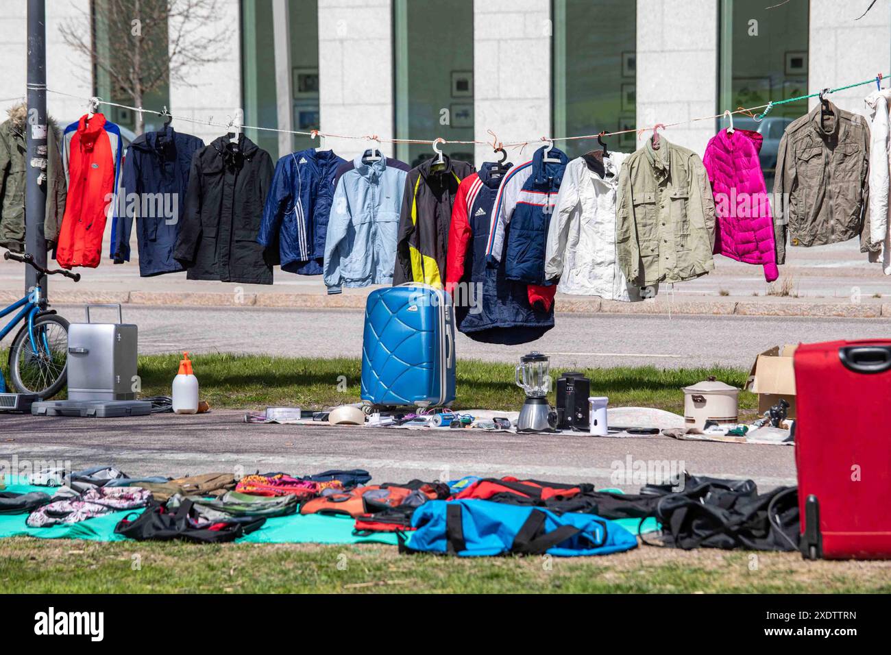 Abiti usati in vendita appesi alla clothesline al mercato delle pulci pop-up all'aperto del parco Dallapé nel quartiere Vallila di Helsinki, Finlandia Foto Stock