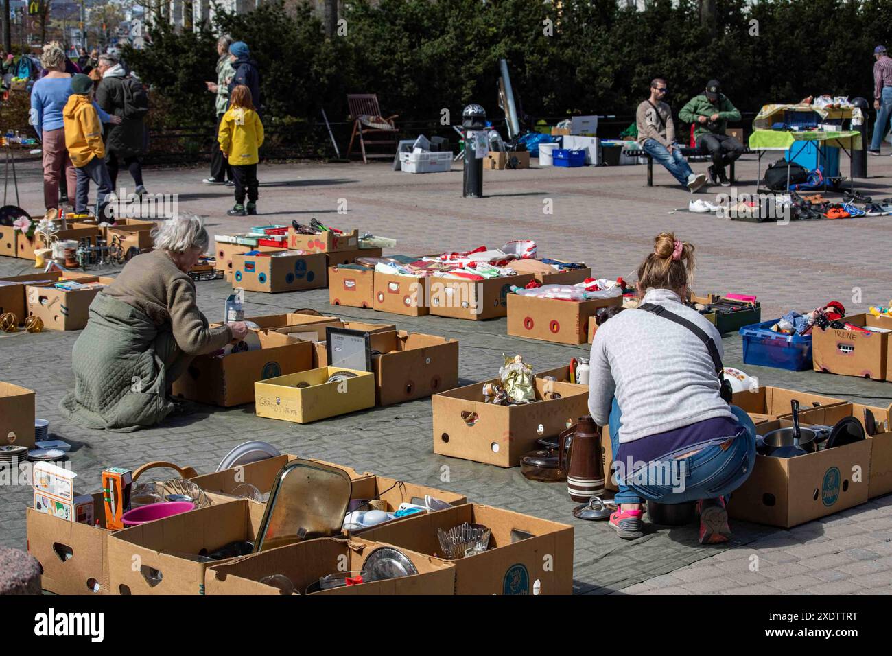 Donne che navigano in scatole di cartone di articoli usati al mercato delle pulci pop-up all'aperto del Dallapé Park nel quartiere Vallila di Helsinki, Finlandia Foto Stock