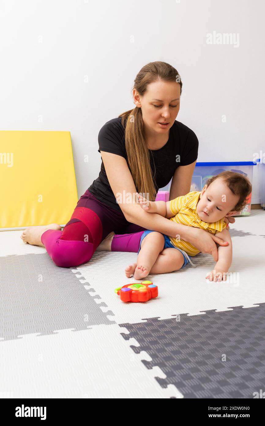 Fisioterapista migliorare il movimento per il bambino con l'aiuto di esercizio fisico in clinica medica di riabilitazione Foto Stock