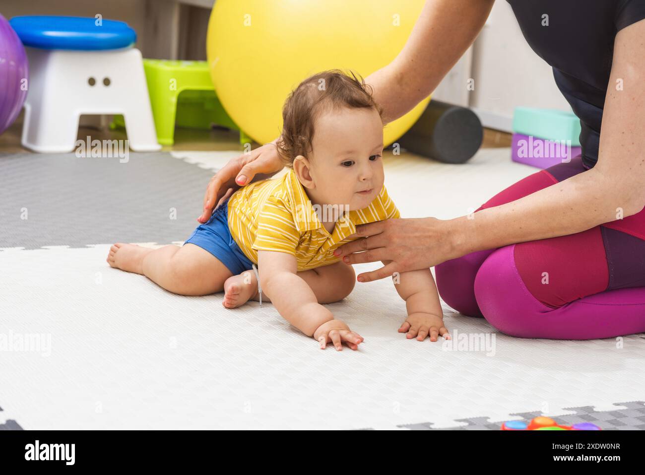 Il fisioterapista aiuta un bambino a sviluppare le sue capacità motorie Foto Stock