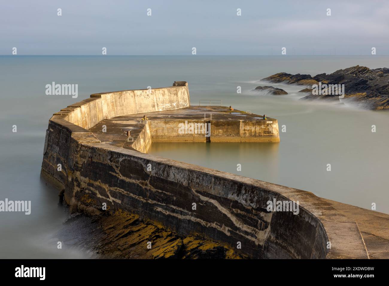Il pittoresco Collieston Harbour nell'Aberdeenshire, Scozia, presenta affascinanti cottage annidati contro aspre scogliere, che si affacciano su un piccolo riparato Foto Stock