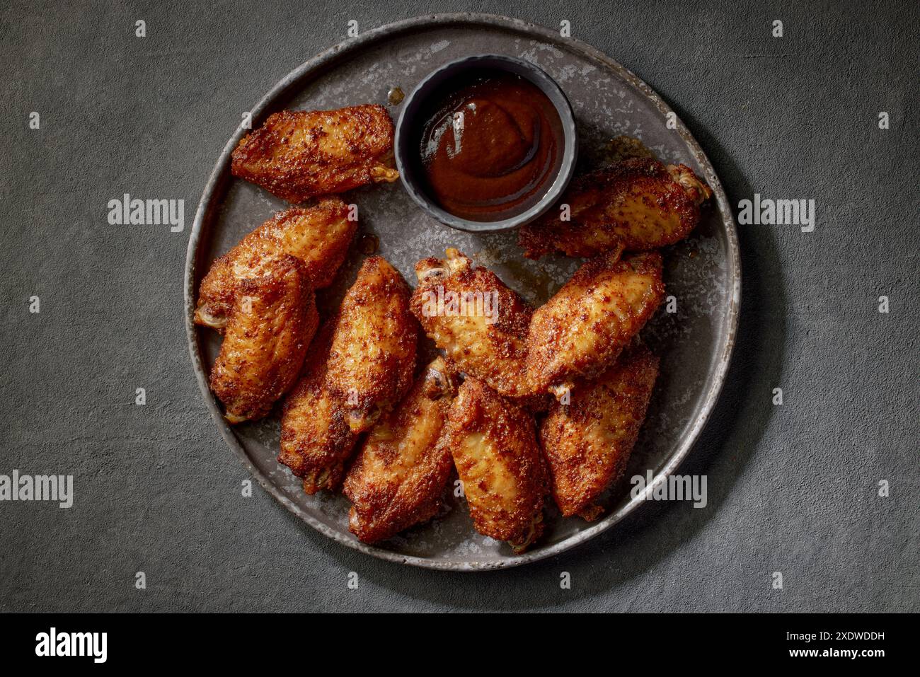 piatto di ali di pollo croccanti appena sfornate sul tavolo grigio, vista dall'alto Foto Stock