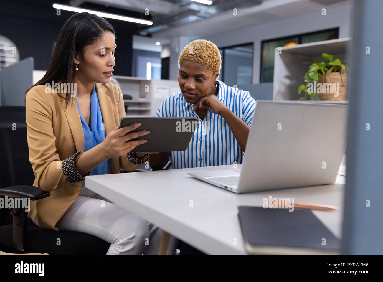 Donne d'affari in ufficio che discutono di un progetto mentre guardano lo schermo di un tablet Foto Stock