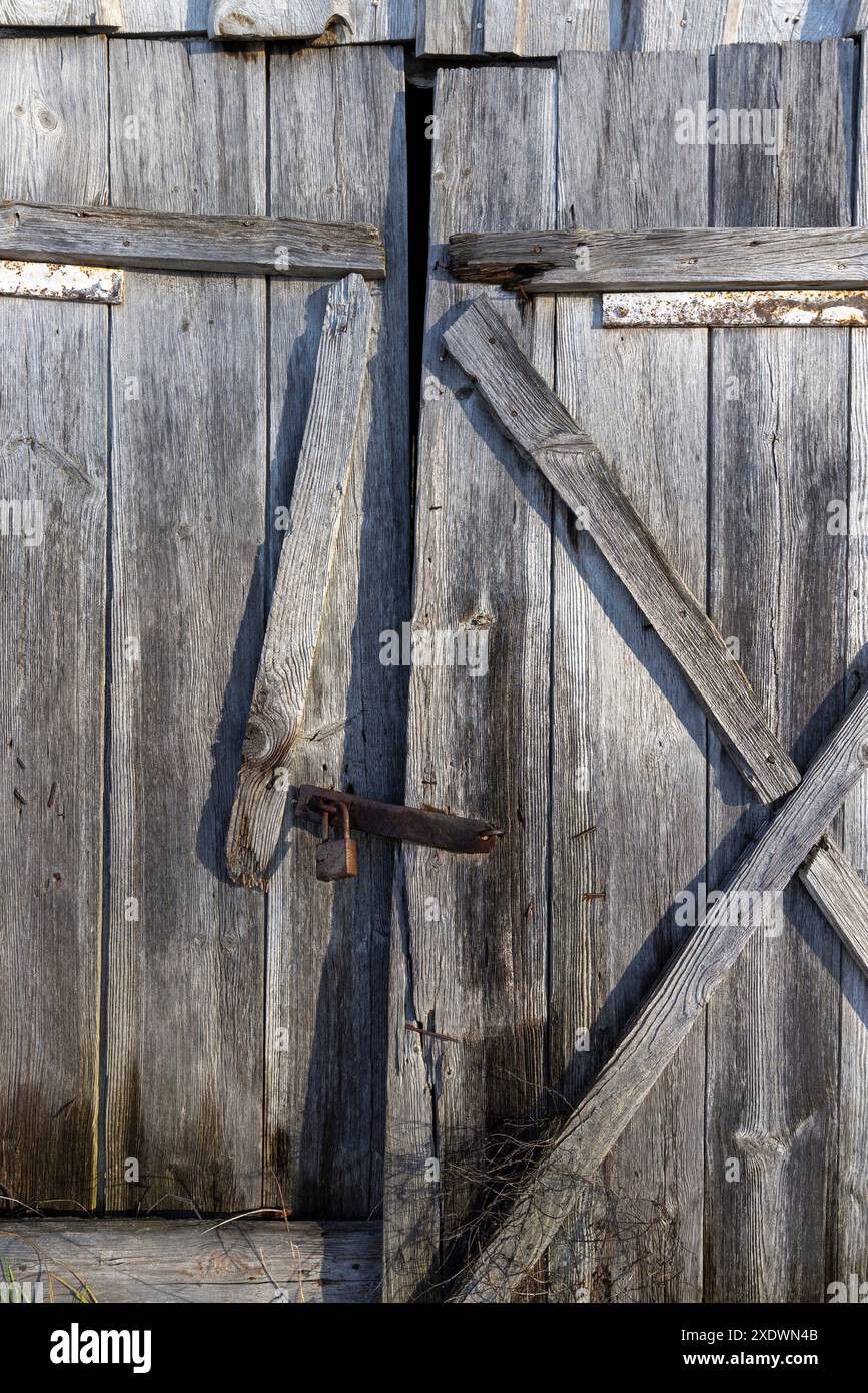 vecchie porte in legno chiuse con lucchetto, parte dell'edificio abbandonato ma con porte chiuse su un lucchetto metallico Foto Stock