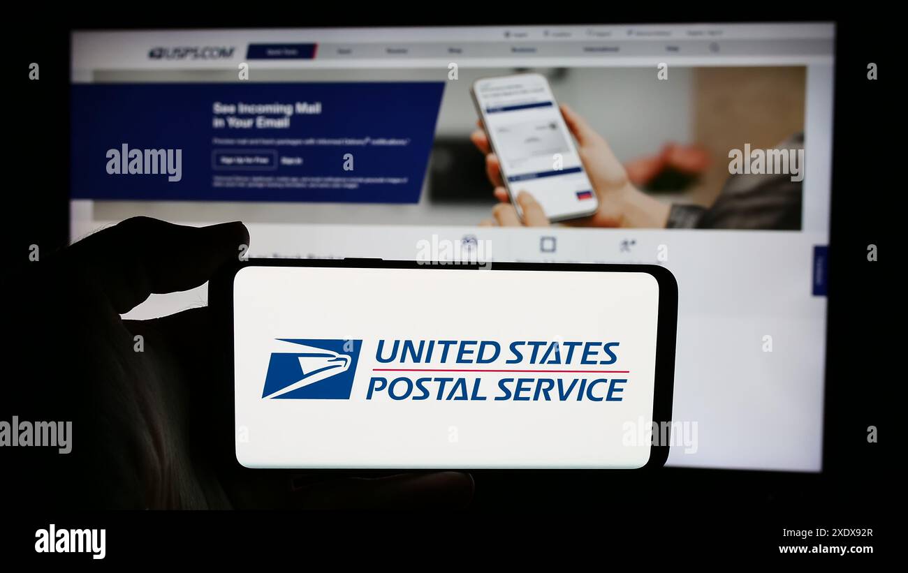 Persona che detiene un cellulare con il logo dell'agenzia statunitense United States Postal Service (USPS) davanti alla pagina web. Mettere a fuoco il display del telefono. Foto Stock