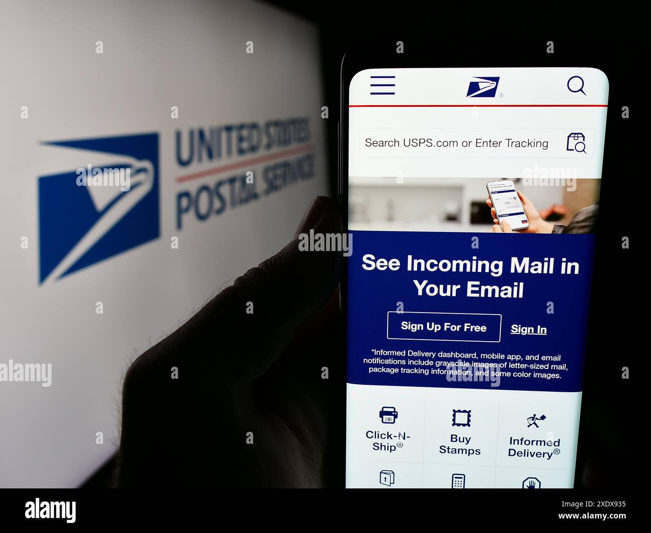 Persona che possiede uno smartphone con la pagina Web dell'agenzia statunitense United States Postal Service (USPS) davanti al logo. Messa a fuoco al centro del display del telefono. Foto Stock