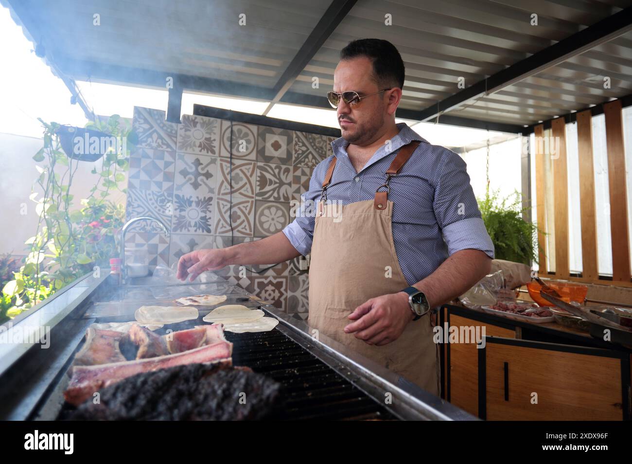 Il giovane cucina a casa carne grigliata al carbone Foto Stock