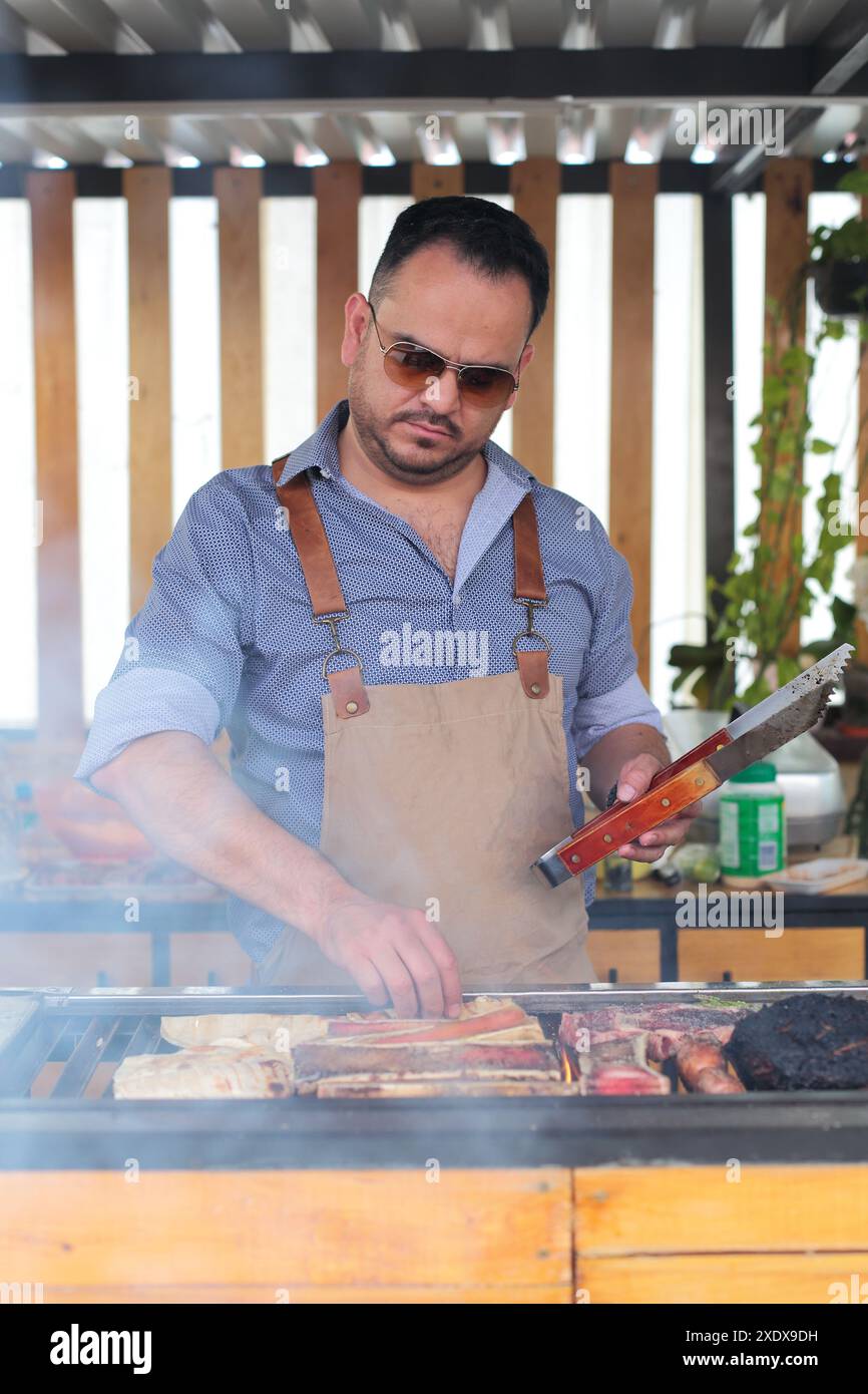 L'uomo mette la carne sulla griglia Foto Stock
