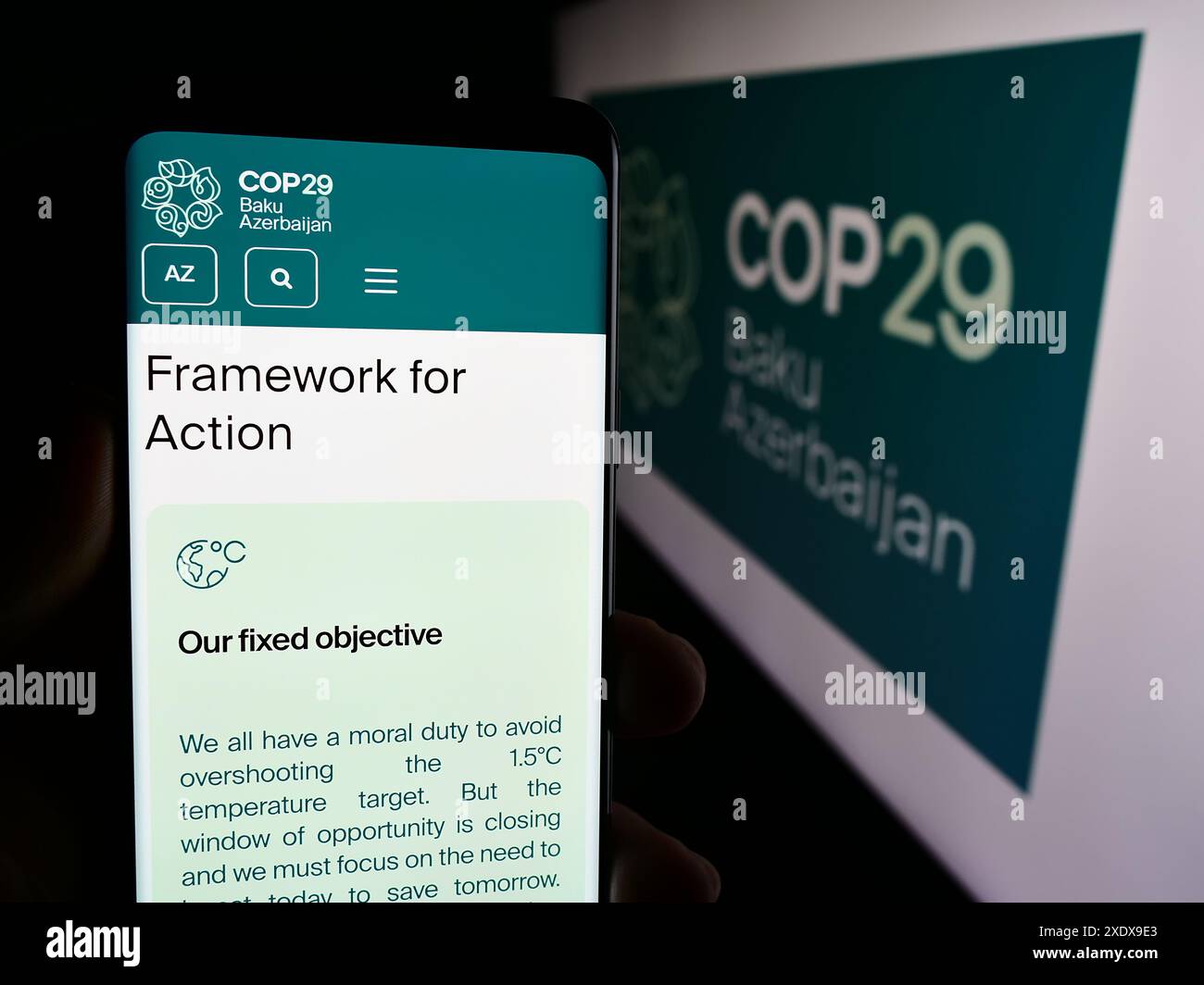 Persona che detiene un cellulare con pagina web della Conferenza delle Nazioni Unite sui cambiamenti climatici 2024 COP29 davanti al logo. Messa a fuoco al centro del display del telefono. Foto Stock