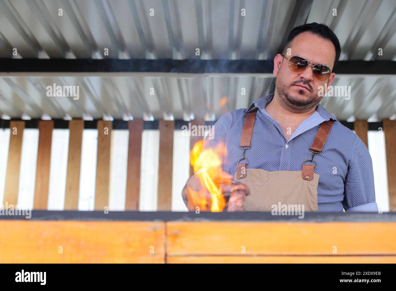 L'uomo gira la carne sulla griglia Foto Stock