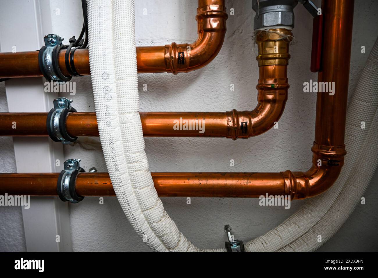 I tubi dell'acqua in rame vengono fissati a una parete da un idraulico durante l'installazione di un impianto di riscaldamento. Foto Stock