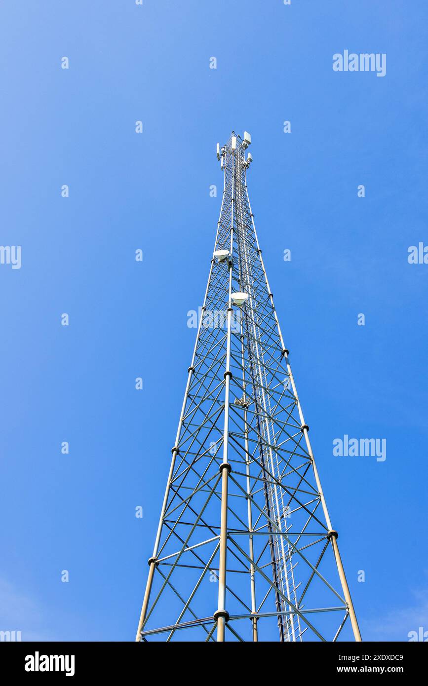 Vista ad angolo basso su una torre radio in un cielo blu chiaro Foto Stock