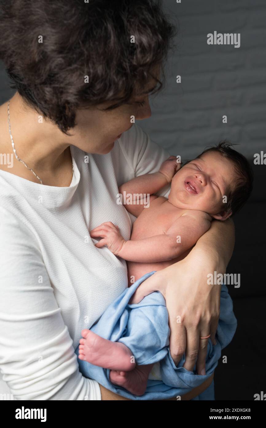 Una madre amorevole si prende cura del suo bambino appena nato a casa. Brillante ritratto di una madre felice che tiene in braccio un bambino. La madre abbraccia il suo figlioletto. Foto Stock