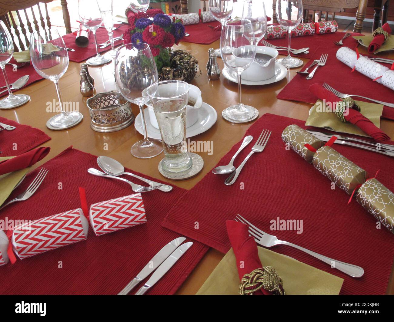 Tavolo da pranzo di Natale per un gruppo di persone al chiuso, tra cui cracker, feste natalizie, cibo e bevande Foto Stock